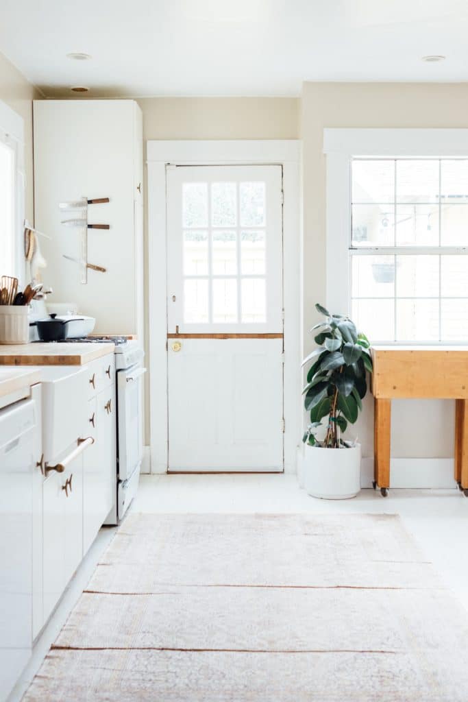 cucina in stile country con porta d'ingresso bianca e tappeto beige