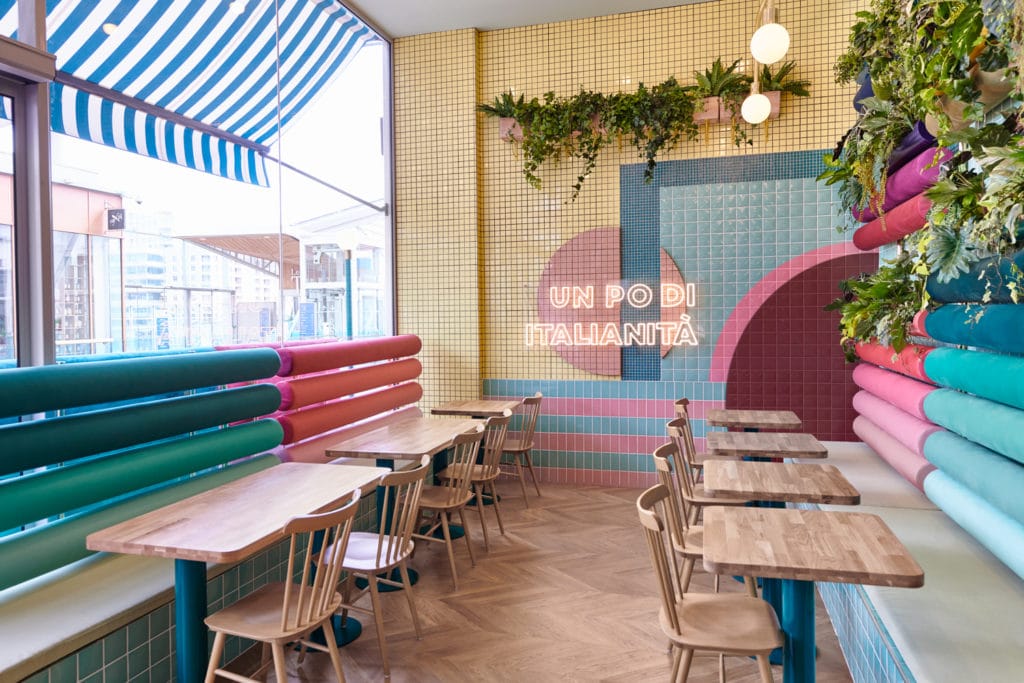 interno del ristorante Piada con dettaglio su tavoli e sedie in legno e panche azzurre e rosa