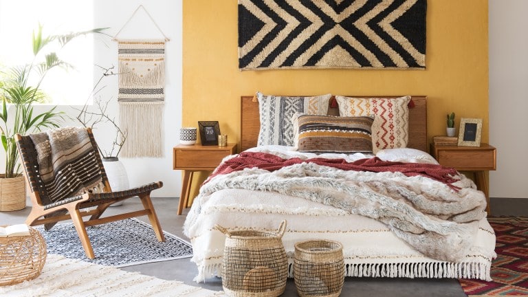Camera da letto in stile etnico con tessuti naturali e accessori in differenti pattern e in colori caldi. 