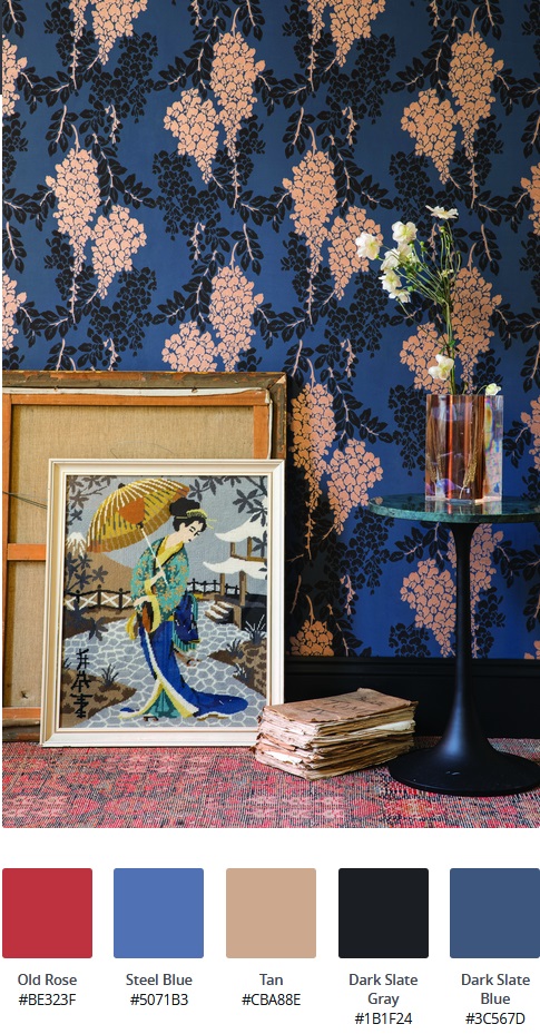 Cos'è lo stile d'arredo massimalista: interno con carta da parati floreale a fondo blu, quadri a tema Giappone, tavolo da caffè rotondo con piano in marmo verde, vaso trasparente con fiori bianchi e tappeto rosso