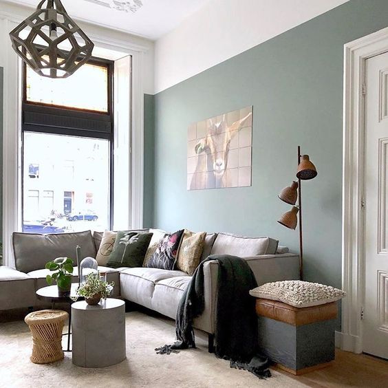 soggiorno arredato nei toni del verde con divano ad angolo grigio 