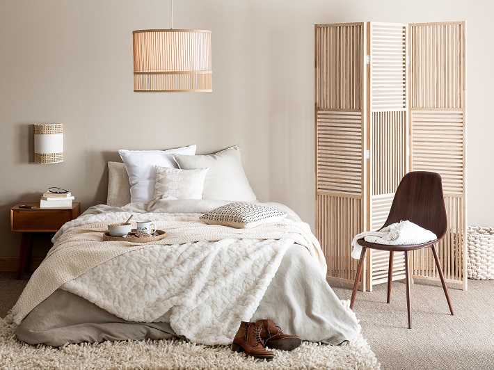 camera da letto in colori neutri con paravento in legno e sedia in palissandro