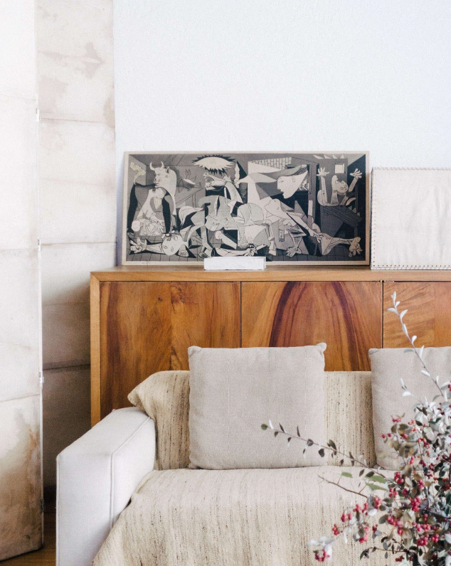 Guernica di Picasso sopra ad una madia in stile moderno con divano bianco