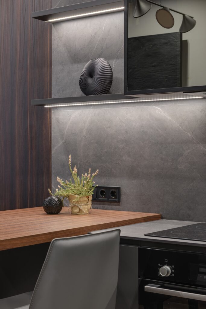 Cucina con paraschizzi e top in ceramica, tutto in grigio scuro e piano snack in noce