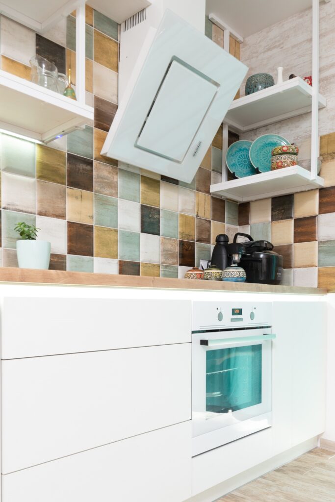 top cucina in legno massello di rovere, su cucian bianca con paraschizzi di piastrelle colorate effetto metallo