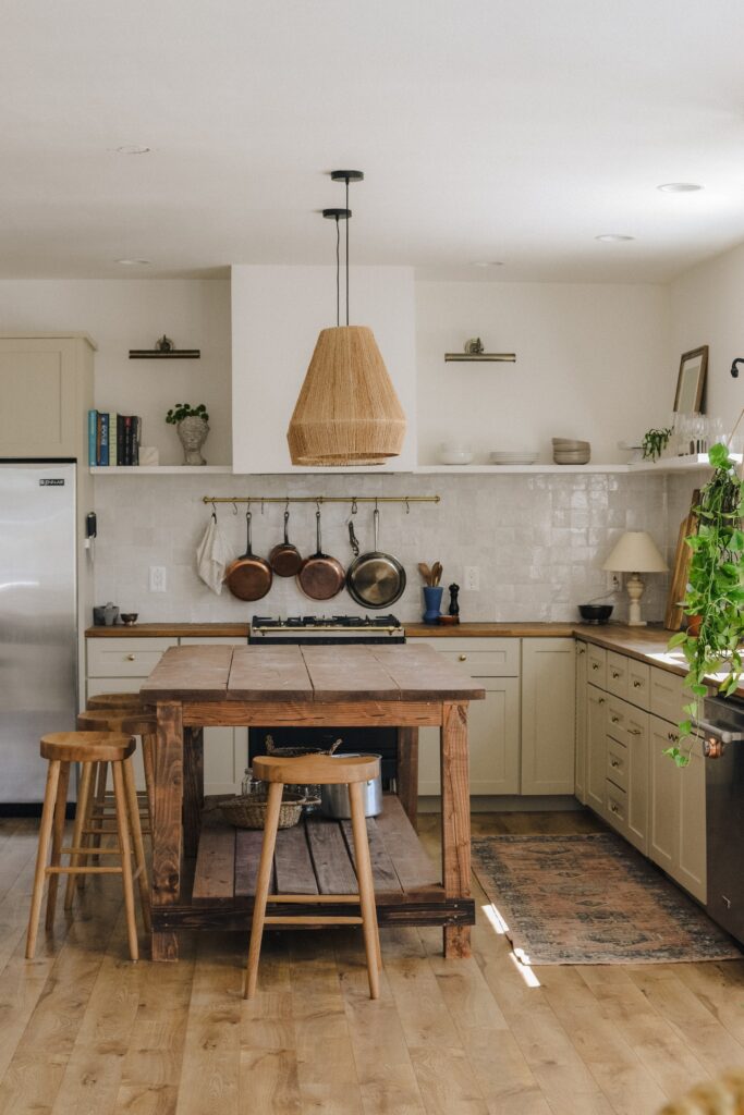cucina rustica con tavolo in legno massello e sgabelli vintage. Paraschizzi in pietre diamante e cucina in bianco opaco